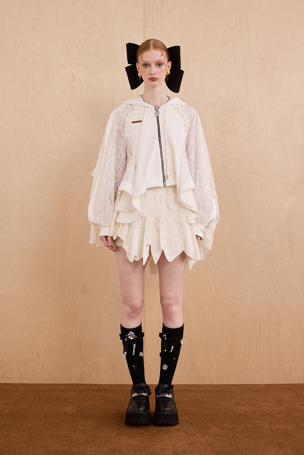 Model wearing loose-fit patchwork caped jacket with elegant lace accents