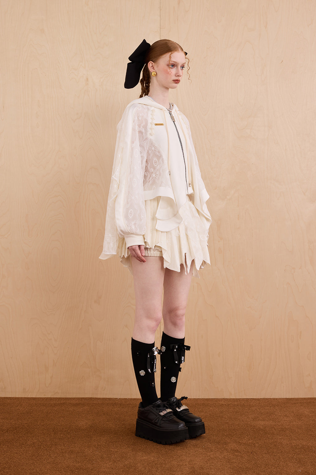 Model wearing loose-fit patchwork caped jacket with elegant lace accents
