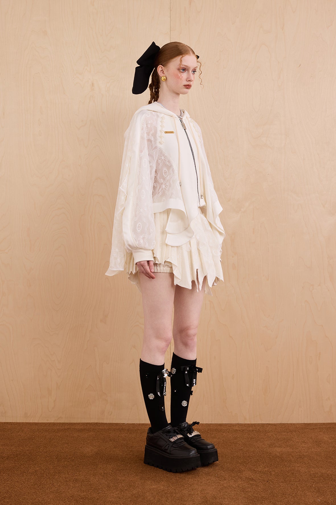 Model wearing loose-fit patchwork caped jacket with elegant lace accents