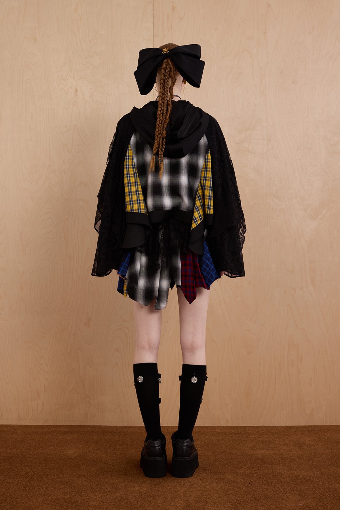 Model wearing loose-fit patchwork caped jacket with elegant lace accents