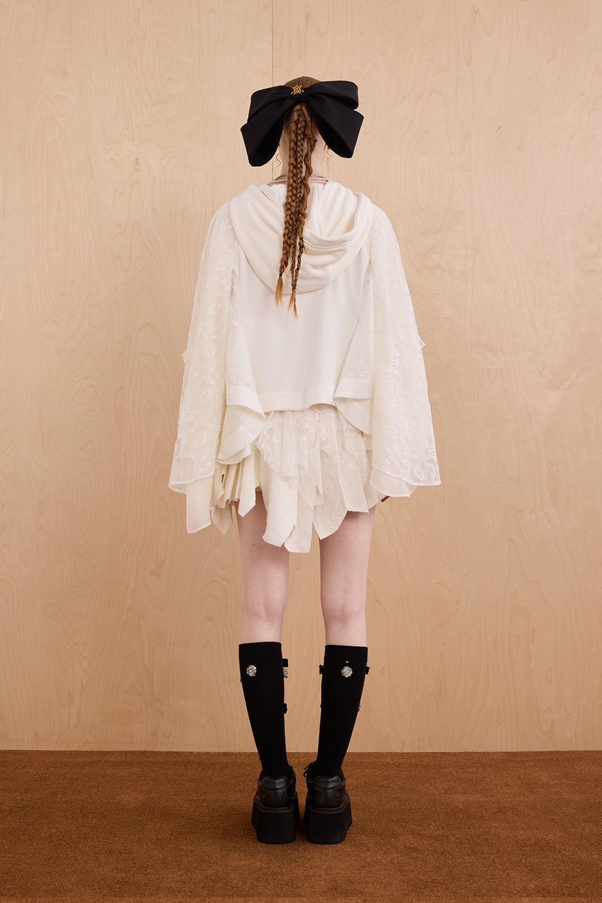 Model wearing loose-fit patchwork caped jacket with elegant lace accents