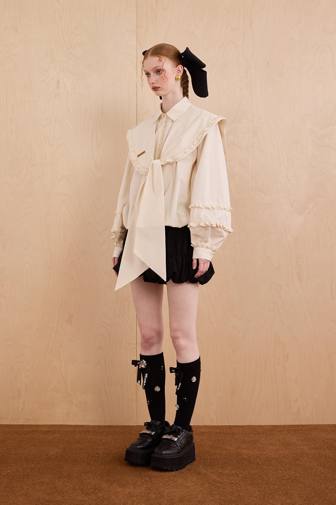 Model wearing a white outfit with black accents against a beige background
