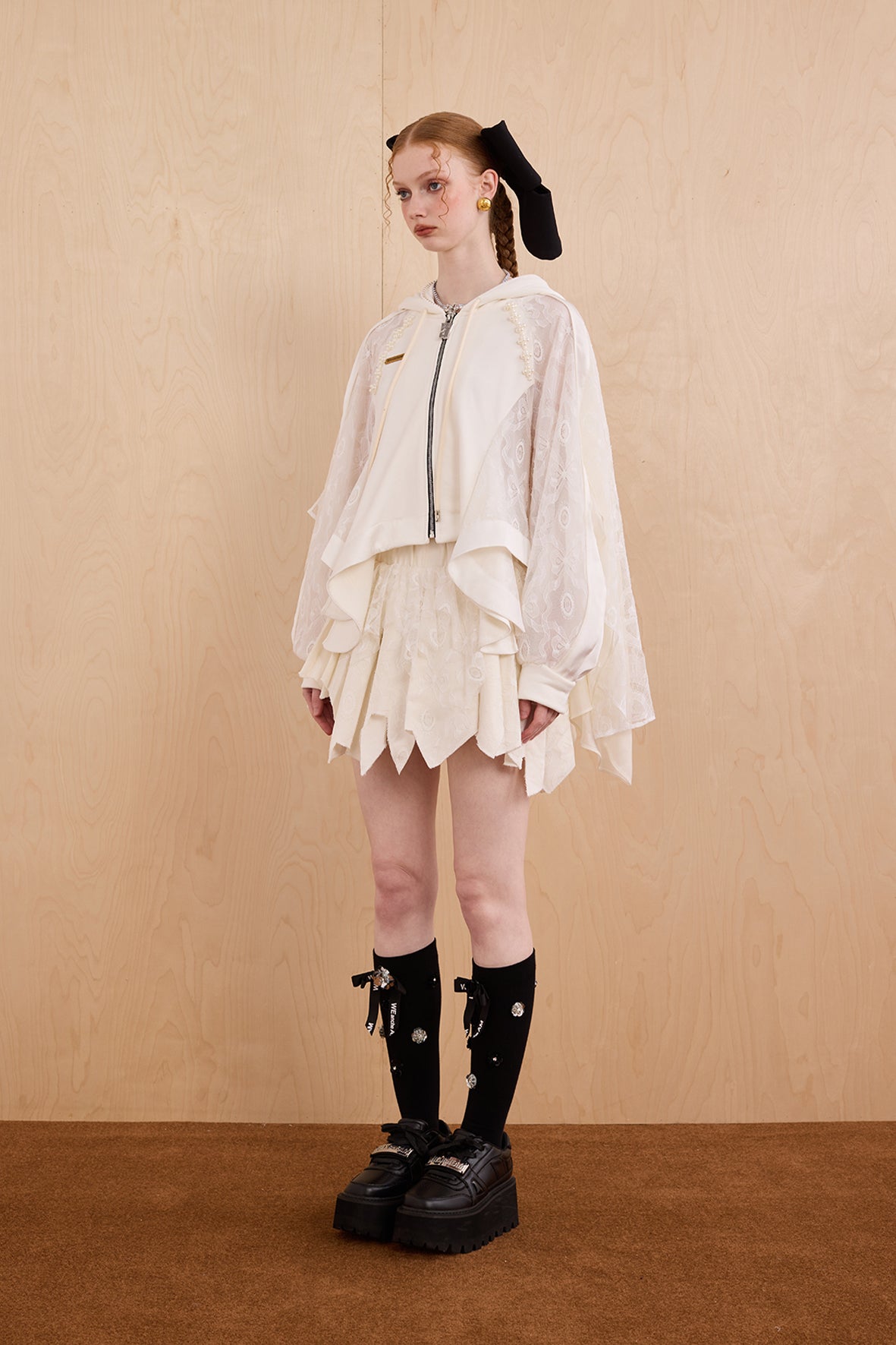 Model wearing loose-fit patchwork caped jacket with elegant lace accents