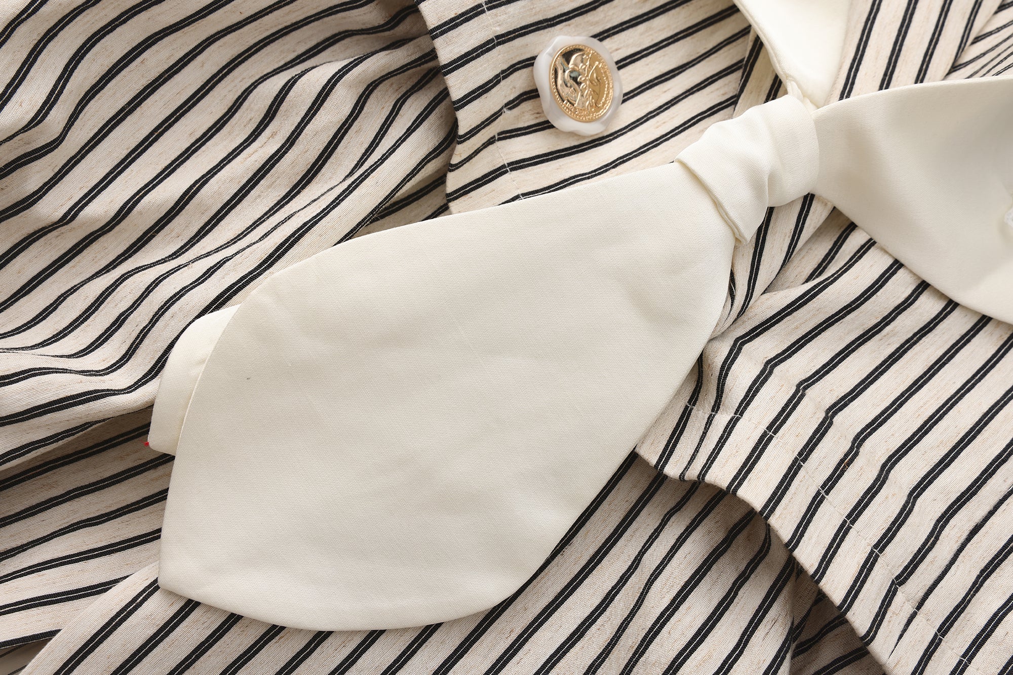 Close-up of pleated hem and patchwork panel details on navy jacket