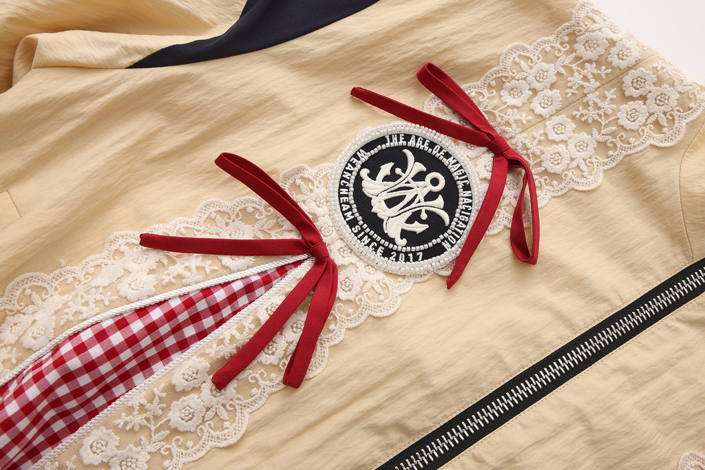 Close-up of lace bow trim and embroidered lace patchwork detail on jacket