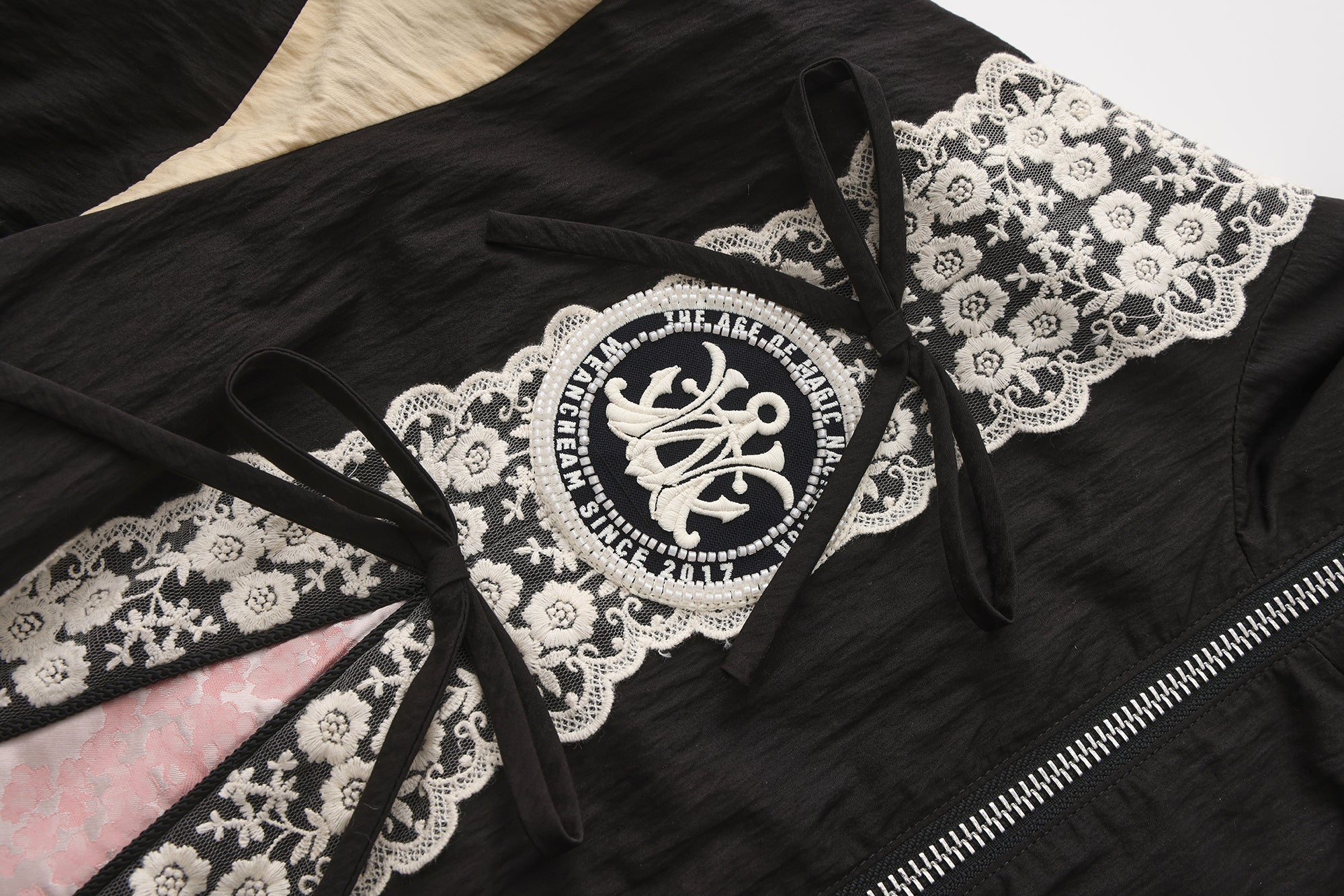 Close-up of lace bow trim and embroidered lace patchwork detail on jacket