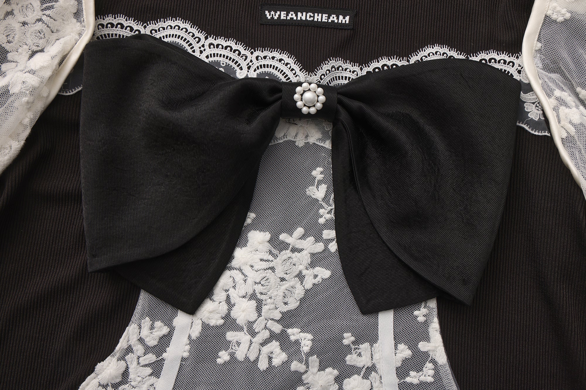 Close-up of lace fabric, detachable sleeve detail, and bow accent on vintage-style top