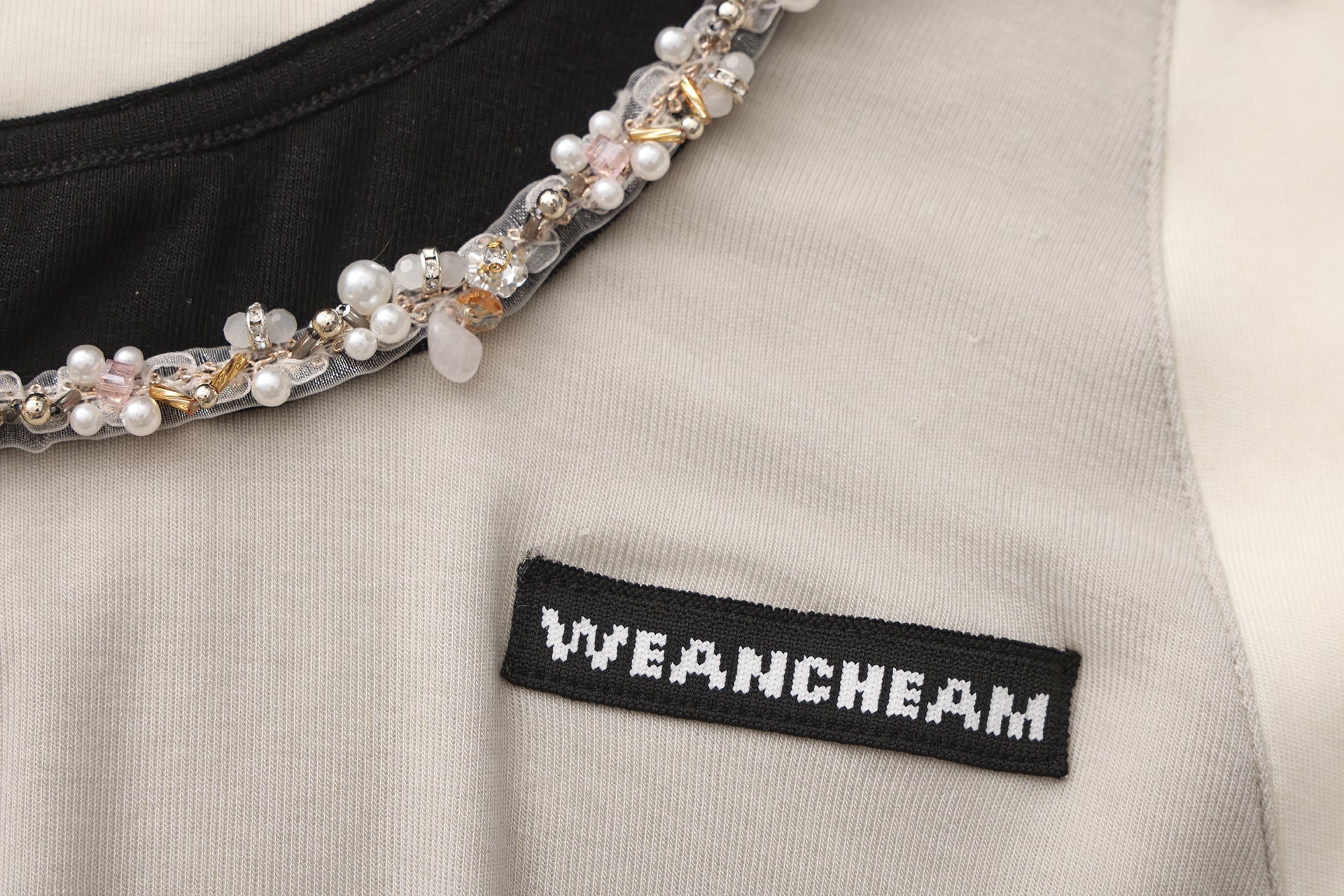 Close-up of beaded floral accent and layered faux two-piece detail on T-shirt