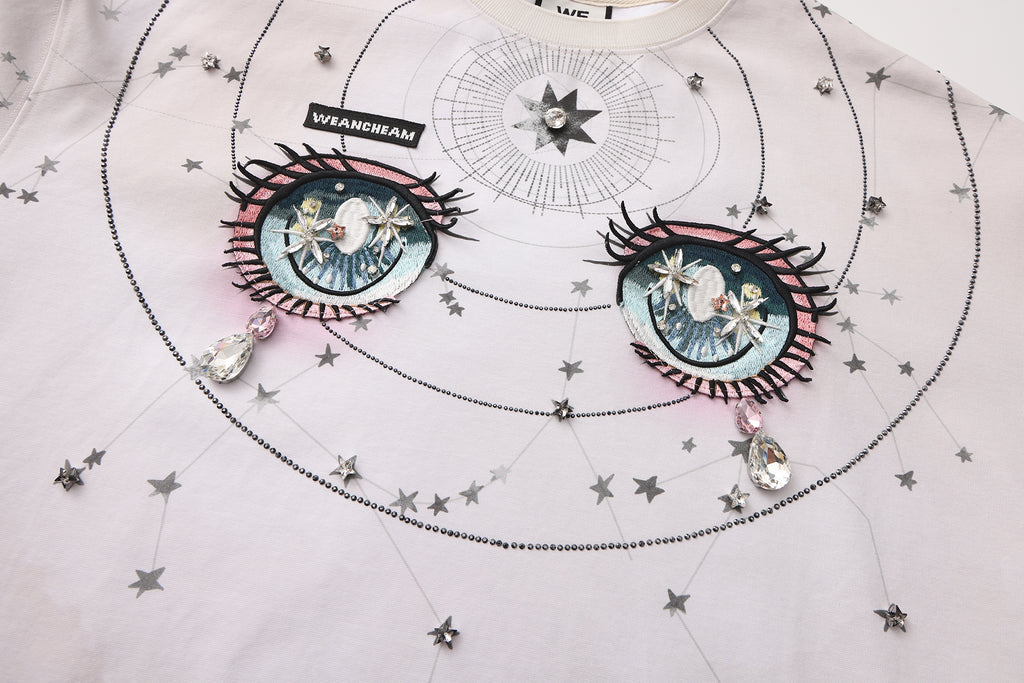 Close-up of crystal-studded stars and 3D embroidered label on long-sleeve cotton tee