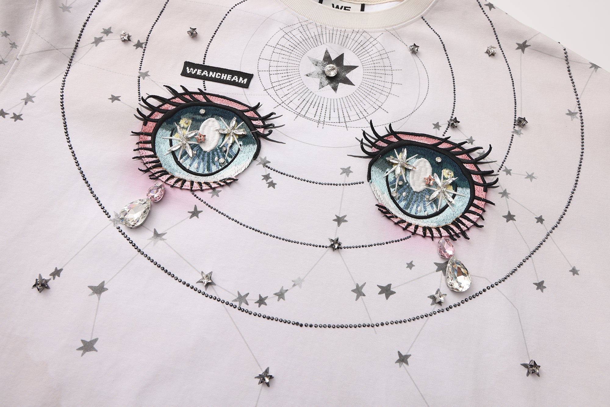 Close-up of crystal-studded stars and 3D embroidered label on long-sleeve cotton tee