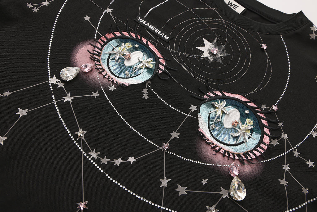 Close-up of crystal-studded stars and 3D embroidered label on long-sleeve cotton tee