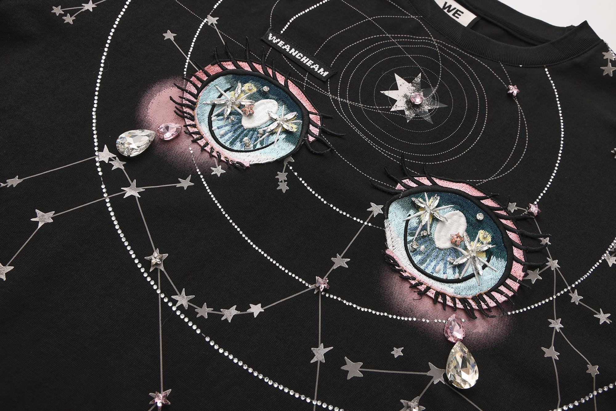 Close-up of crystal-studded stars and 3D embroidered label on long-sleeve cotton tee