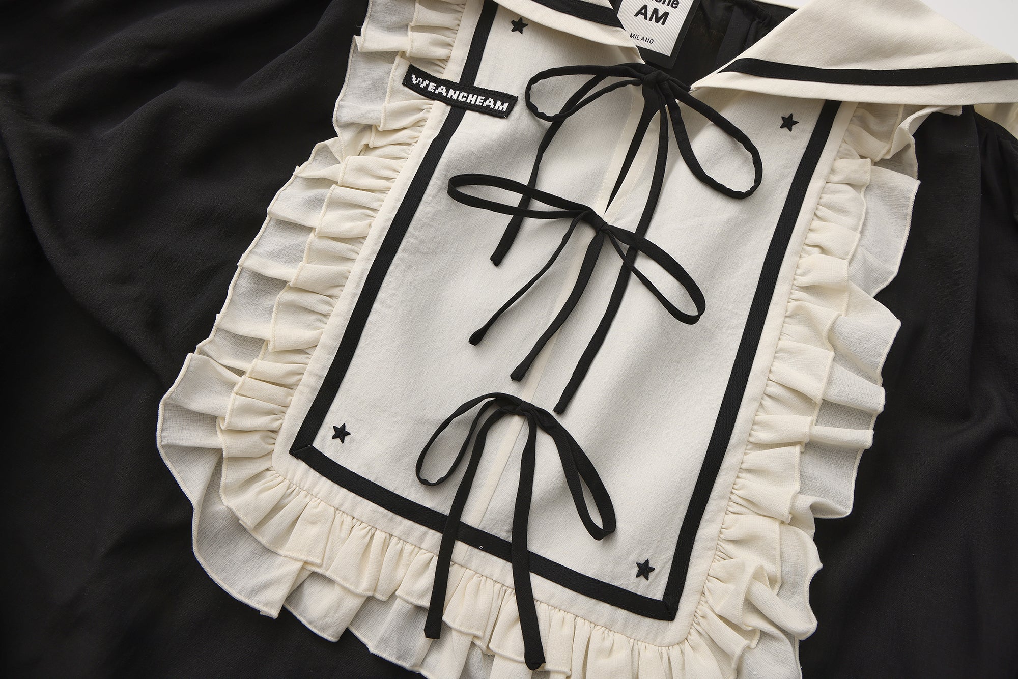 Close-up of lace trim and ribbon bow detail on navy lapel blazer