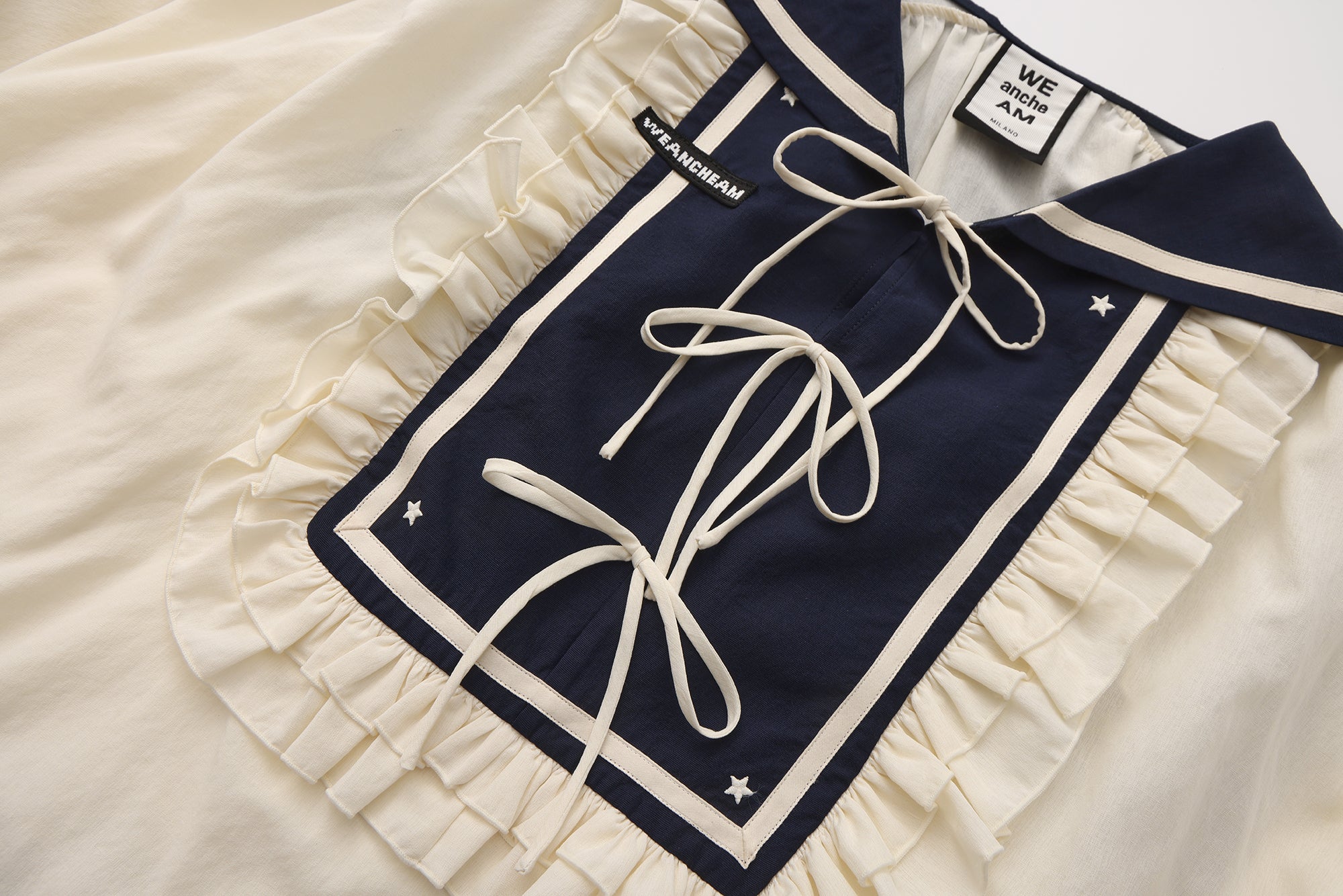 Close-up of lace trim and ribbon bow detail on navy lapel blazer