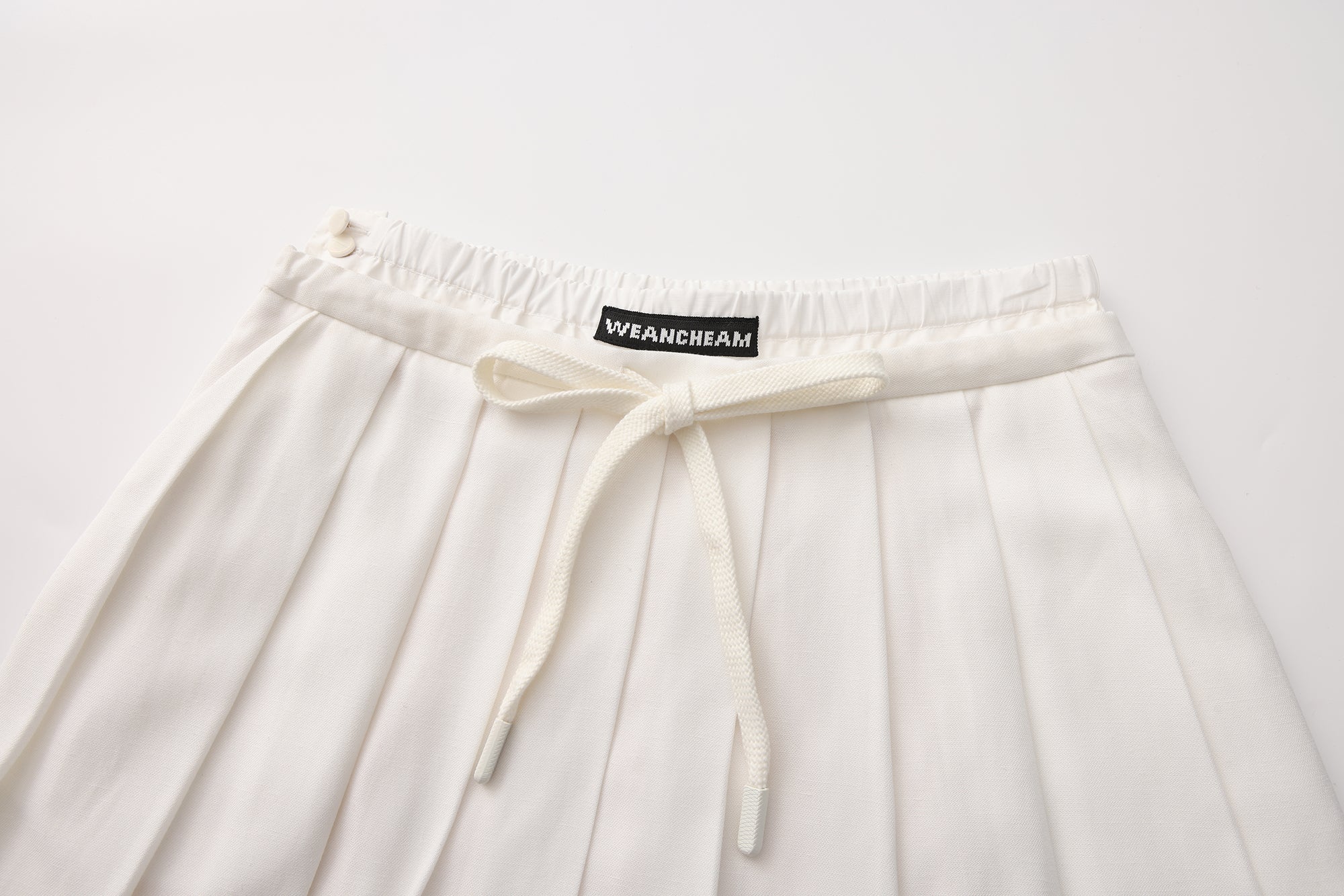 Close-up of lace-trim hem and double waistband detail on pleated skirt