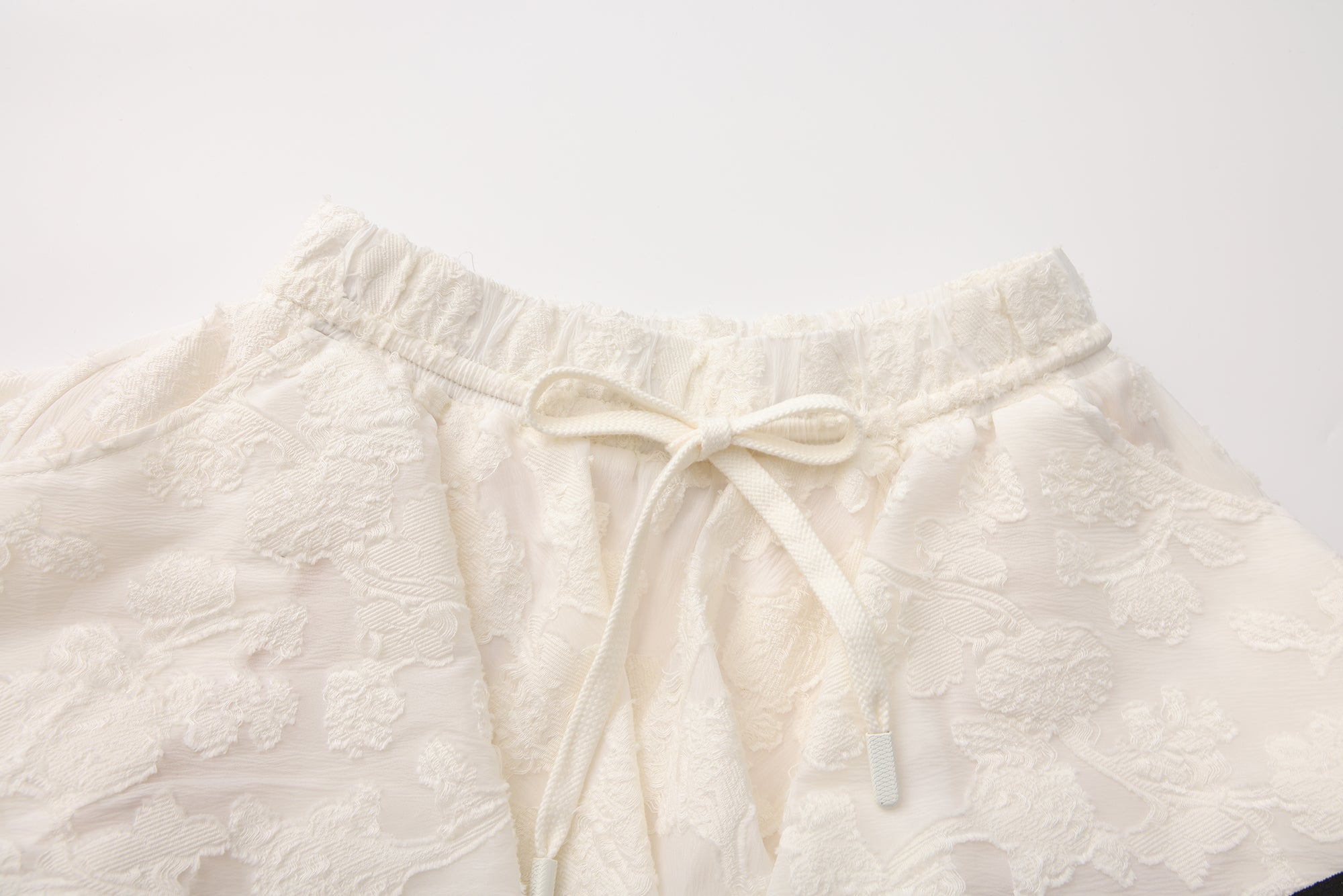 Close-up of elastic waistband and layered pleated wool-blend skirt detail