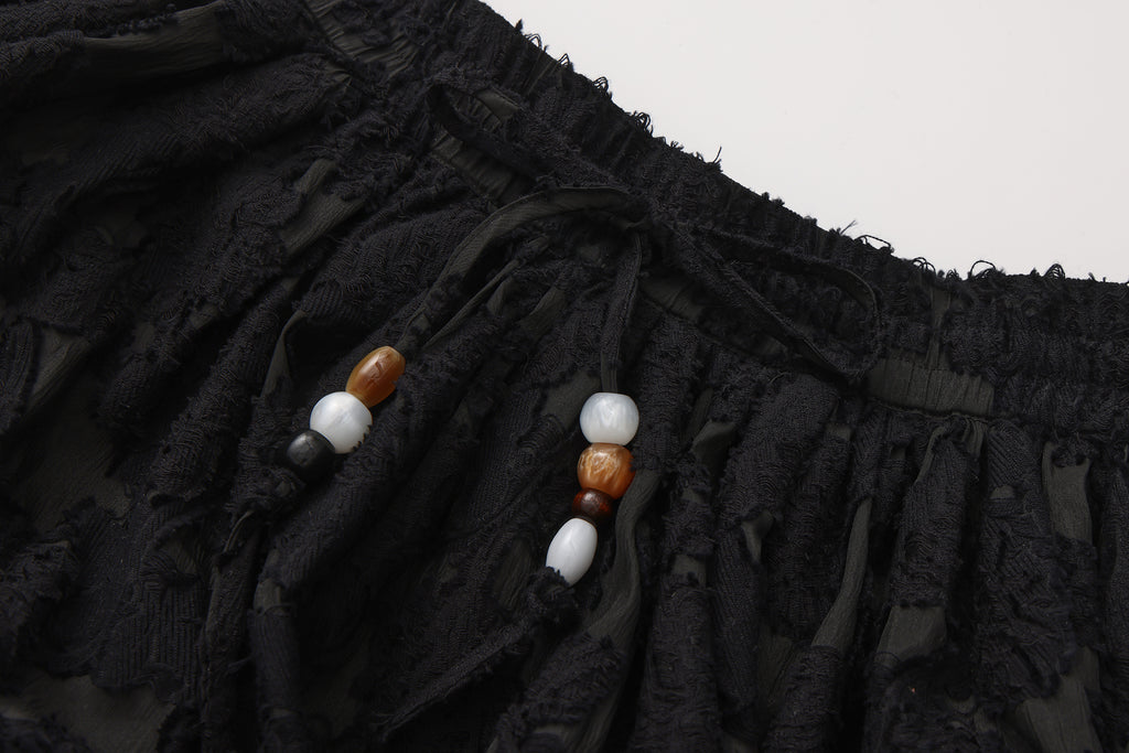 Close-up of lace hem, fishbone silhouette, and beaded waist detail on skirt