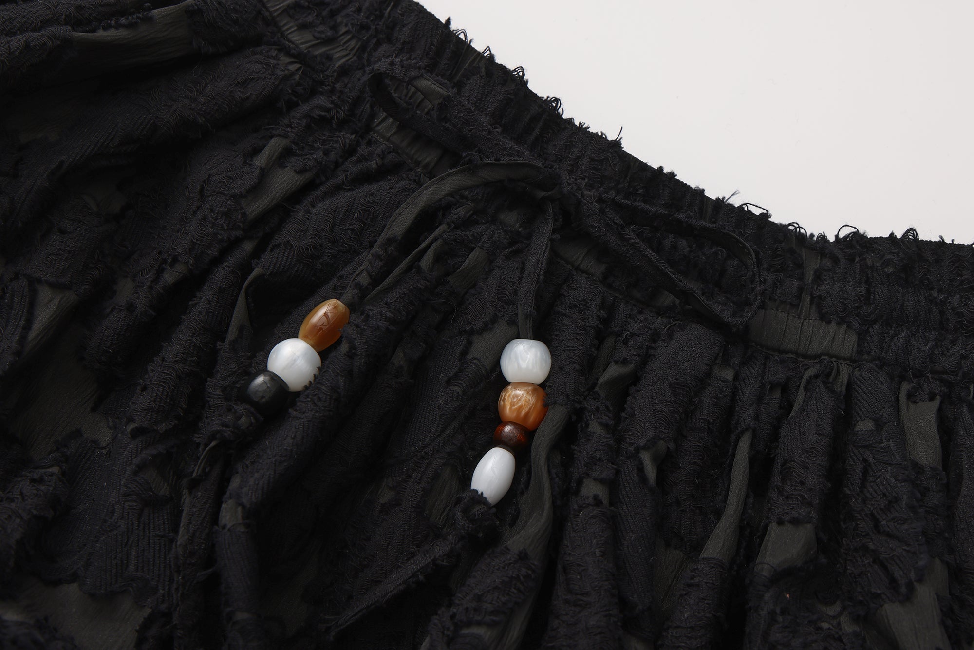 Close-up of lace hem, fishbone silhouette, and beaded waist detail on skirt