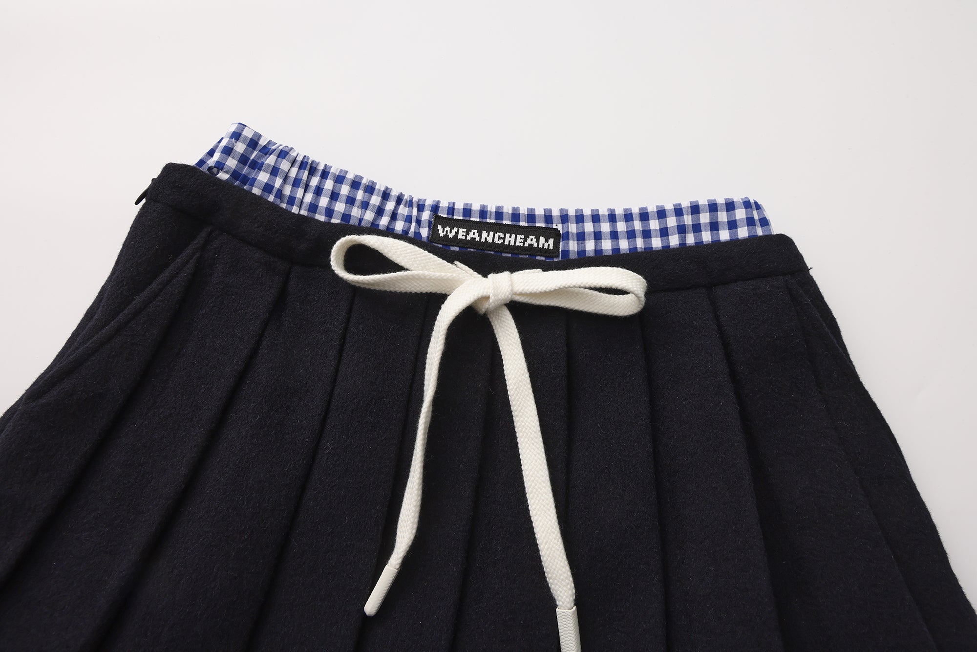 Close-up of lace-trim hem and double waistband detail on pleated skirt