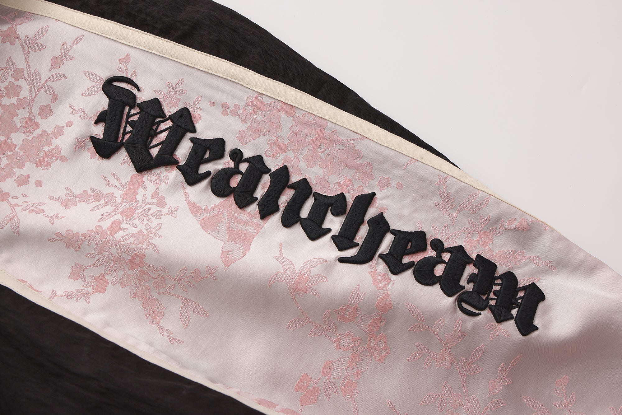 Close-up of embroidered lace patchwork and bow trim detail on trousers