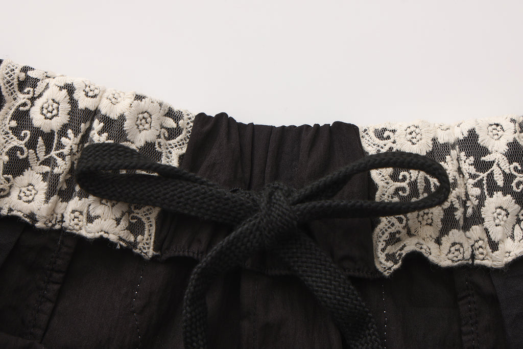 Close-up of embroidered lace patchwork and bow trim detail on trousers