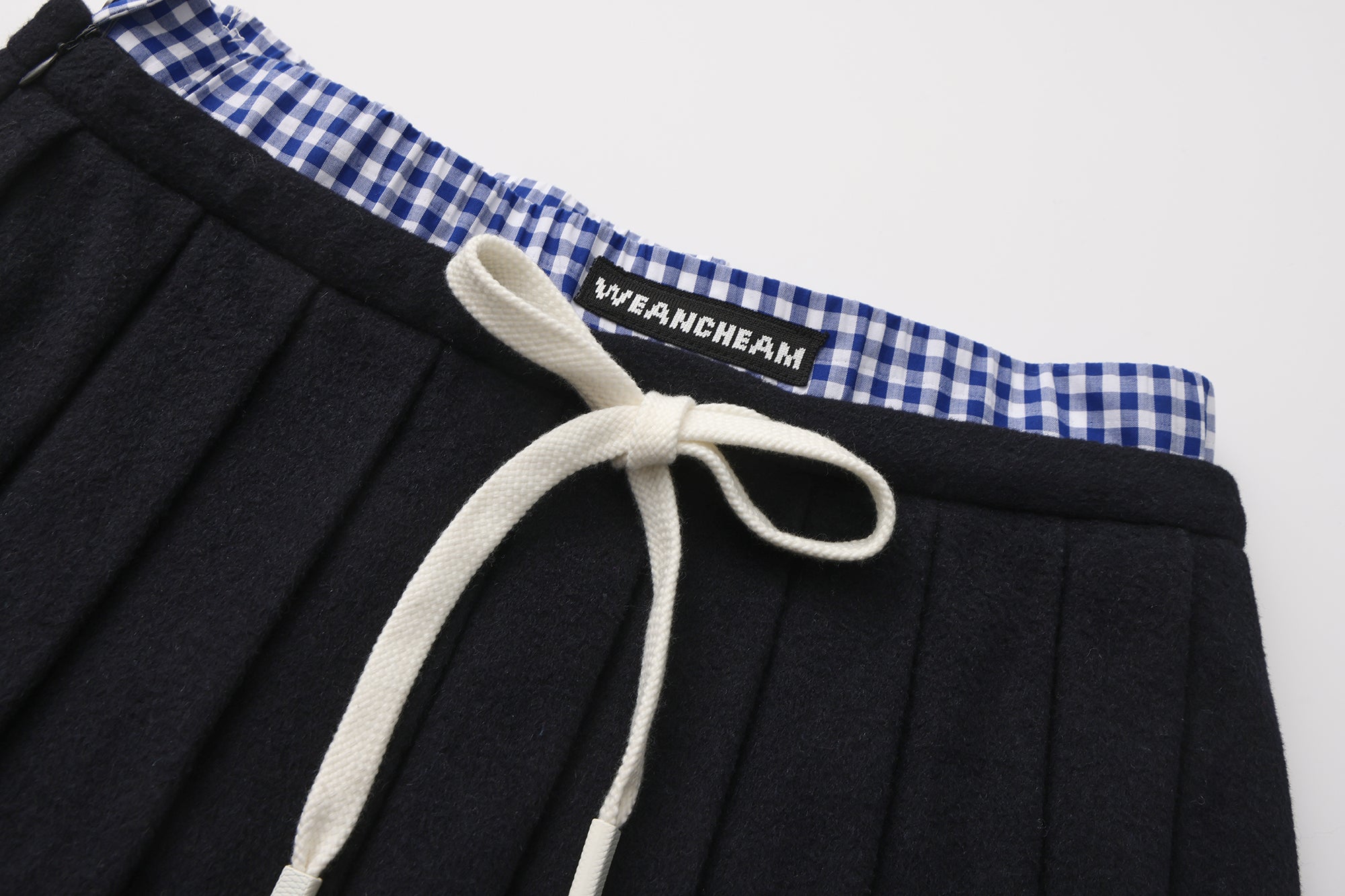 Close-up of pleated fabric and checkered contrast on wool-cashmere skirt