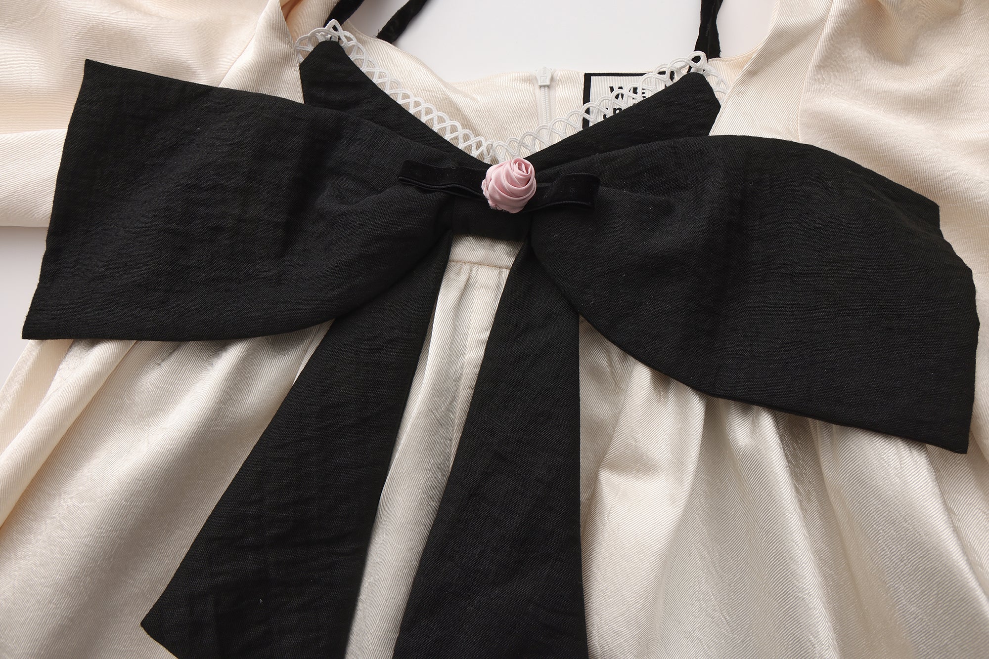 Close-up of sculptural bow and layered neckline on two-piece dress