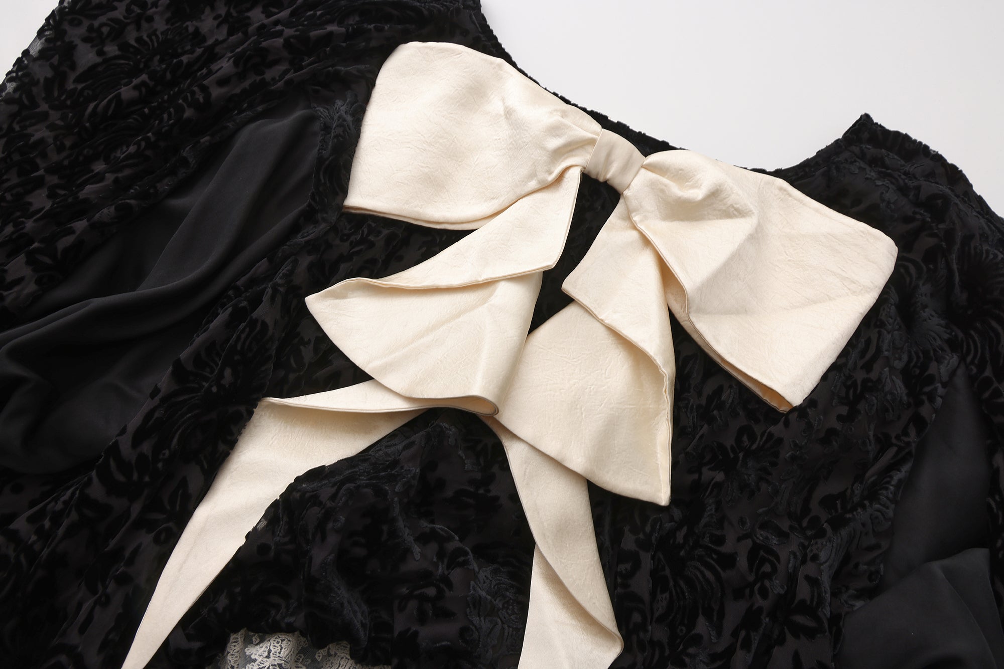 Close-up of ribbon bow detail and high-low hem on flowing dress