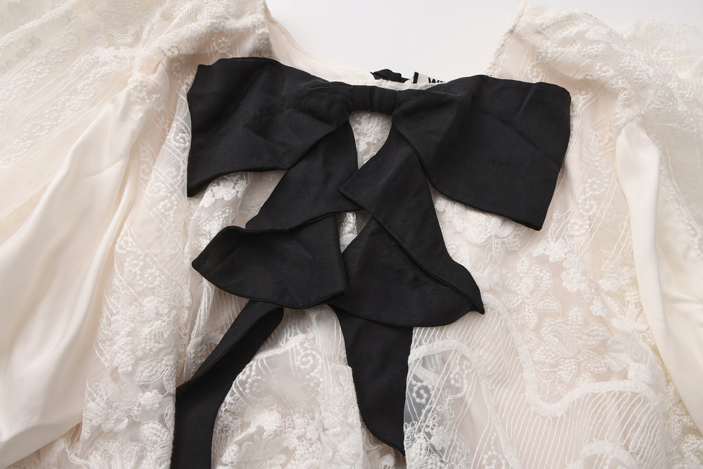 Close-up of ribbon bow detail and high-low hem on flowing dress