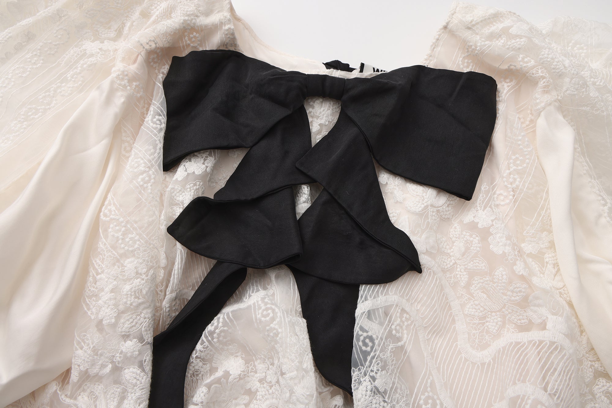 Close-up of ribbon bow detail and high-low hem on flowing dress