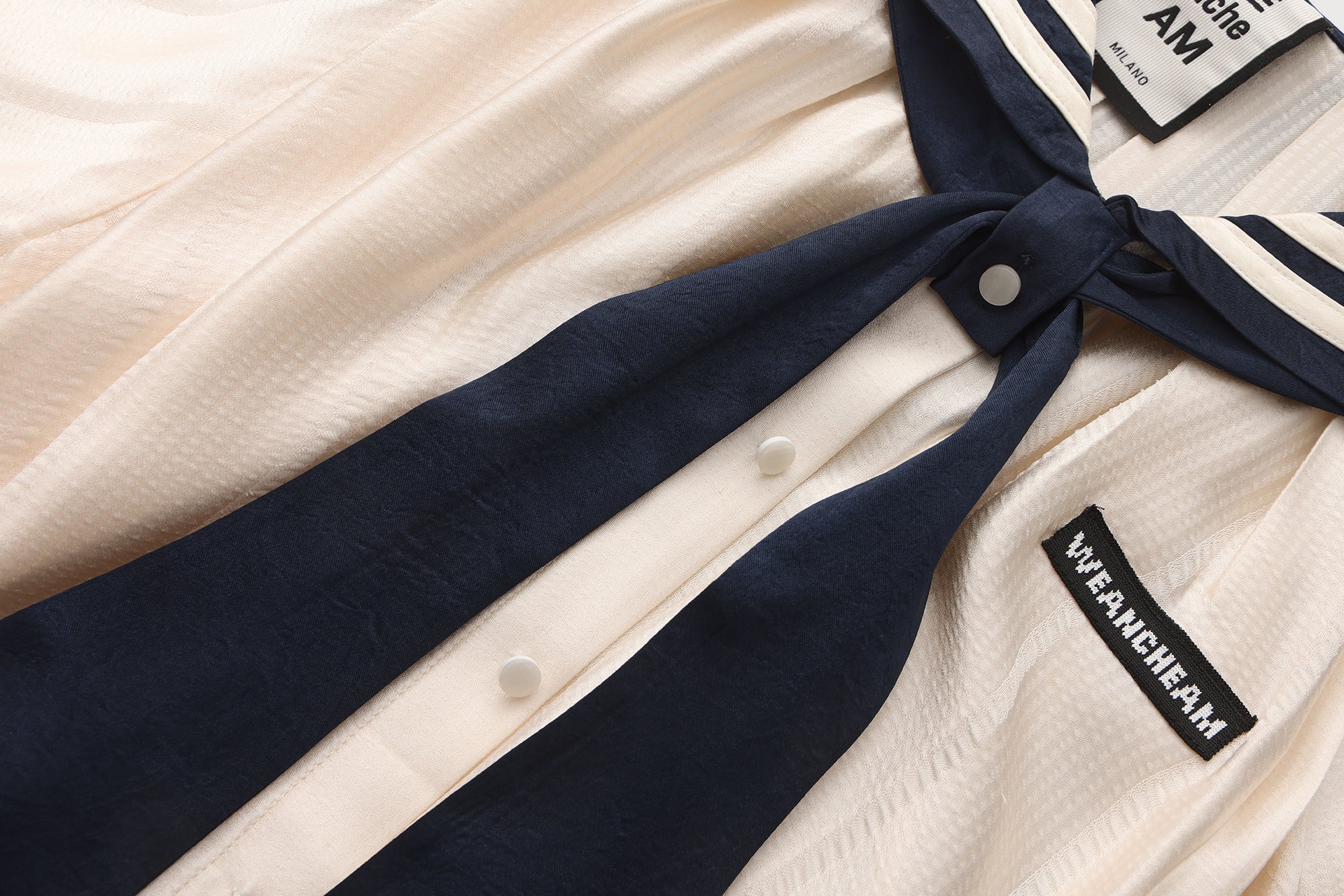 Close-up of ribbon neckline and smooth breathable fabric on navy collar dress