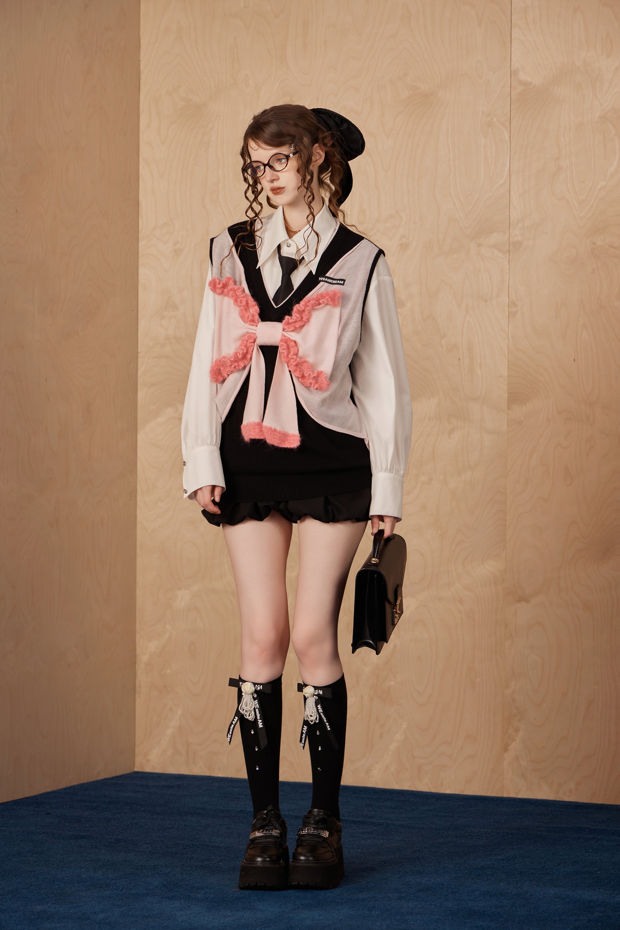 Model wearing knitted tank top sweater vest with bow detail and soft drape