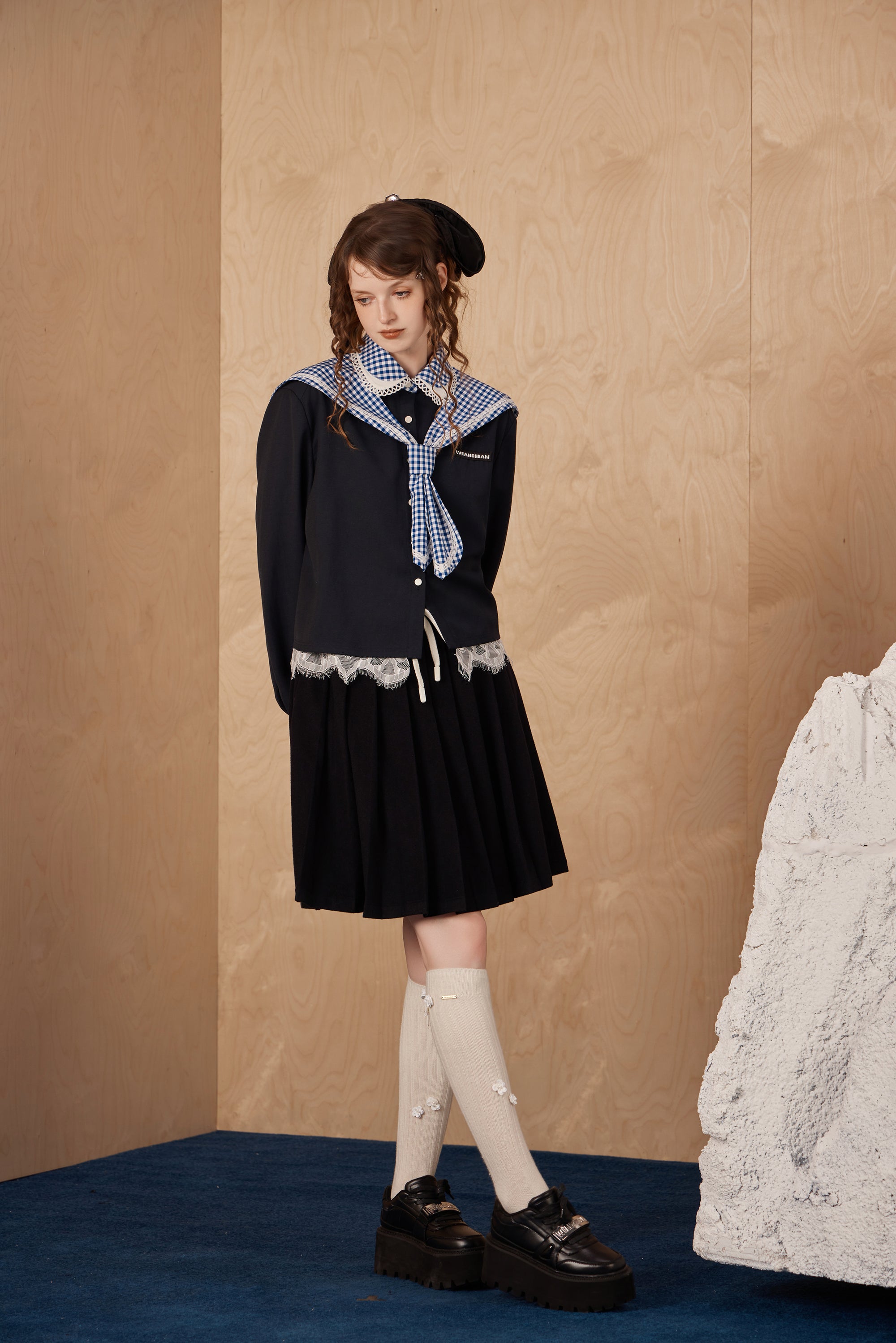 Model wearing double pleated midi skirt with hidden waistband and checkered accents