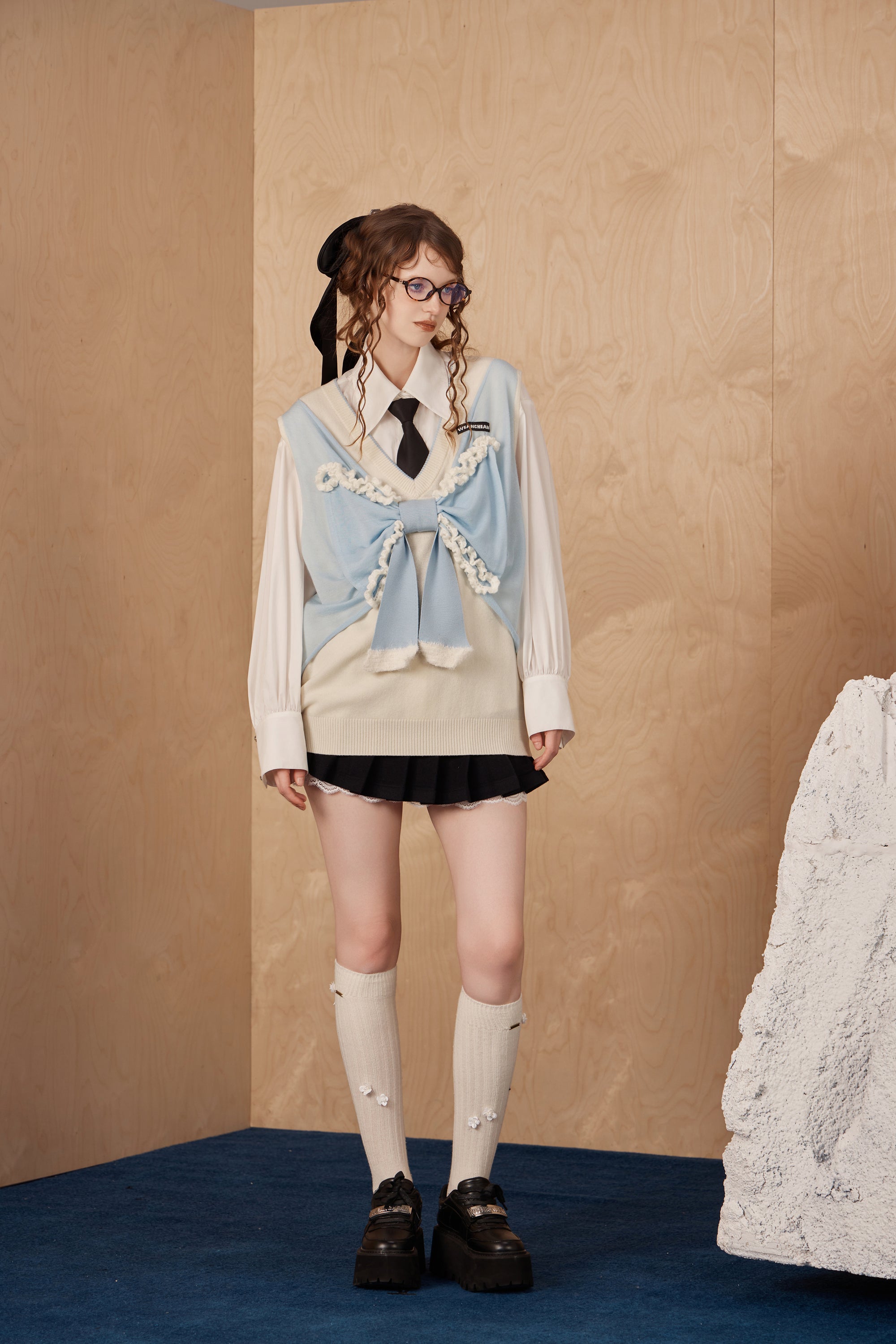 Model wearing knitted tank top sweater vest with bow detail and soft drape