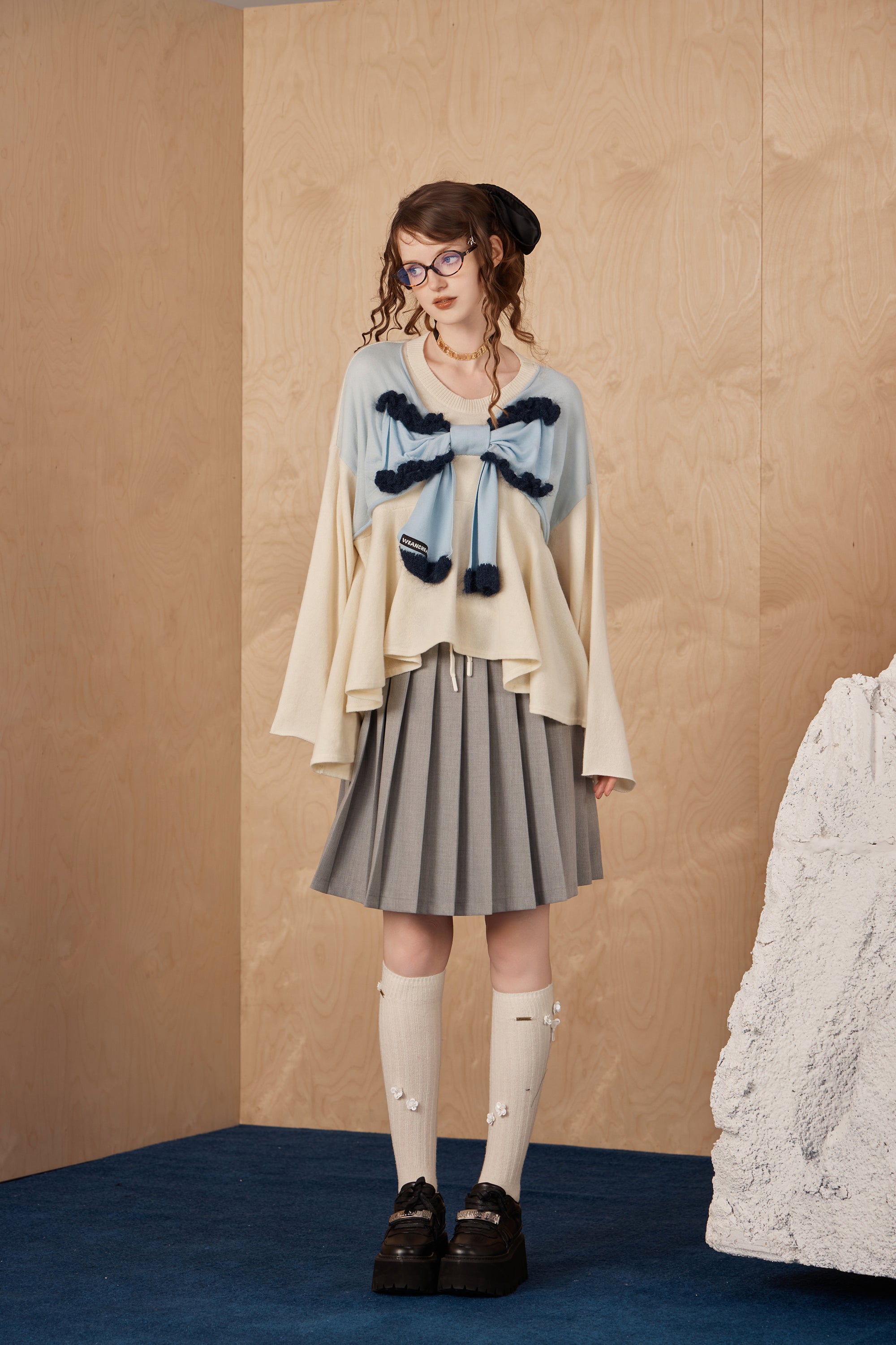 Model wearing double pleated midi skirt with hidden waistband and checkered accents